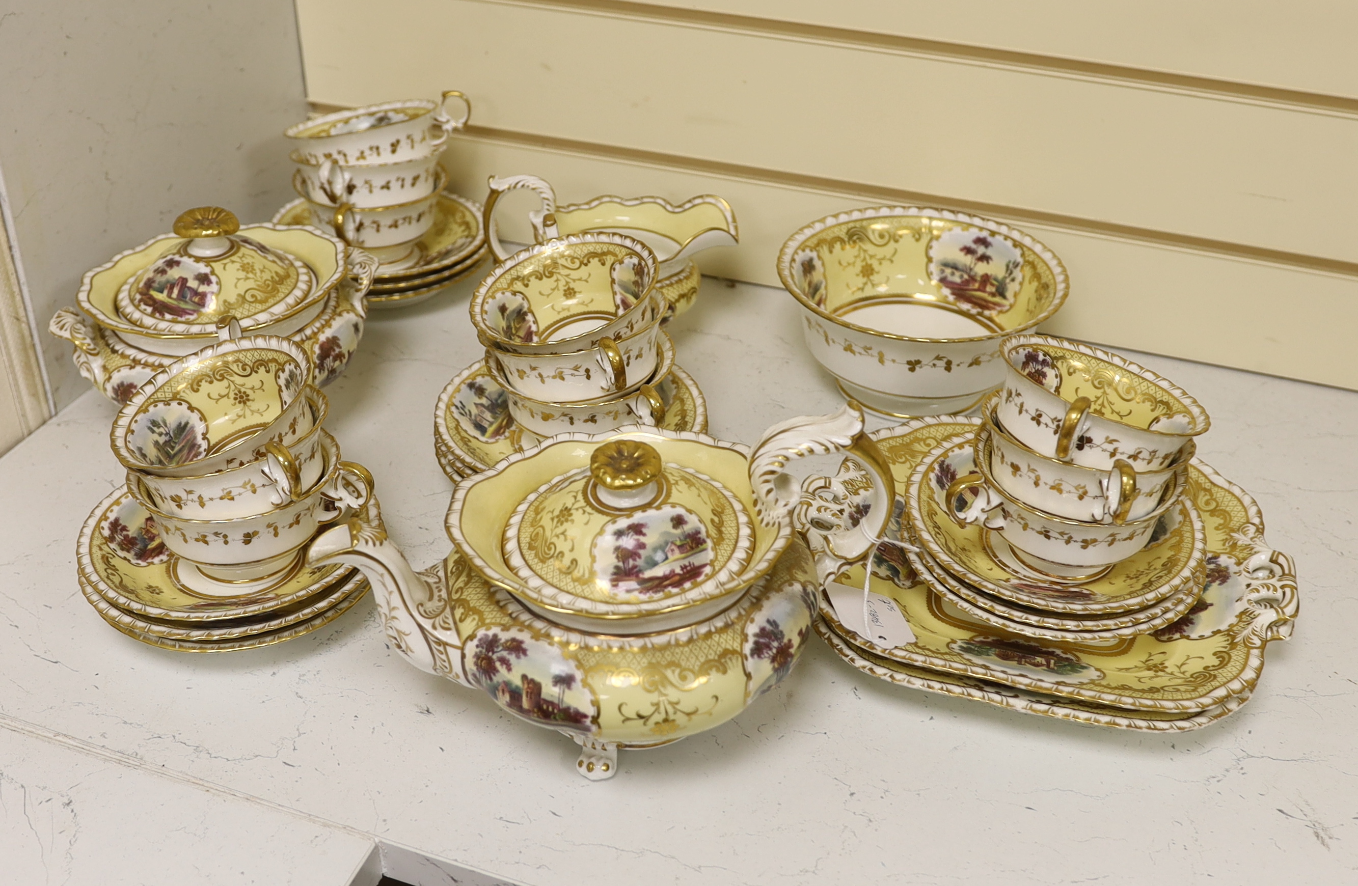 An English porcelain tea set, c.1835-45, including a teapot and cover, sucrier and cover, slops bowl, milk jug, teacups and saucers, two cake plates, each piece painted with buildings in landscapes, yellow ground, patter